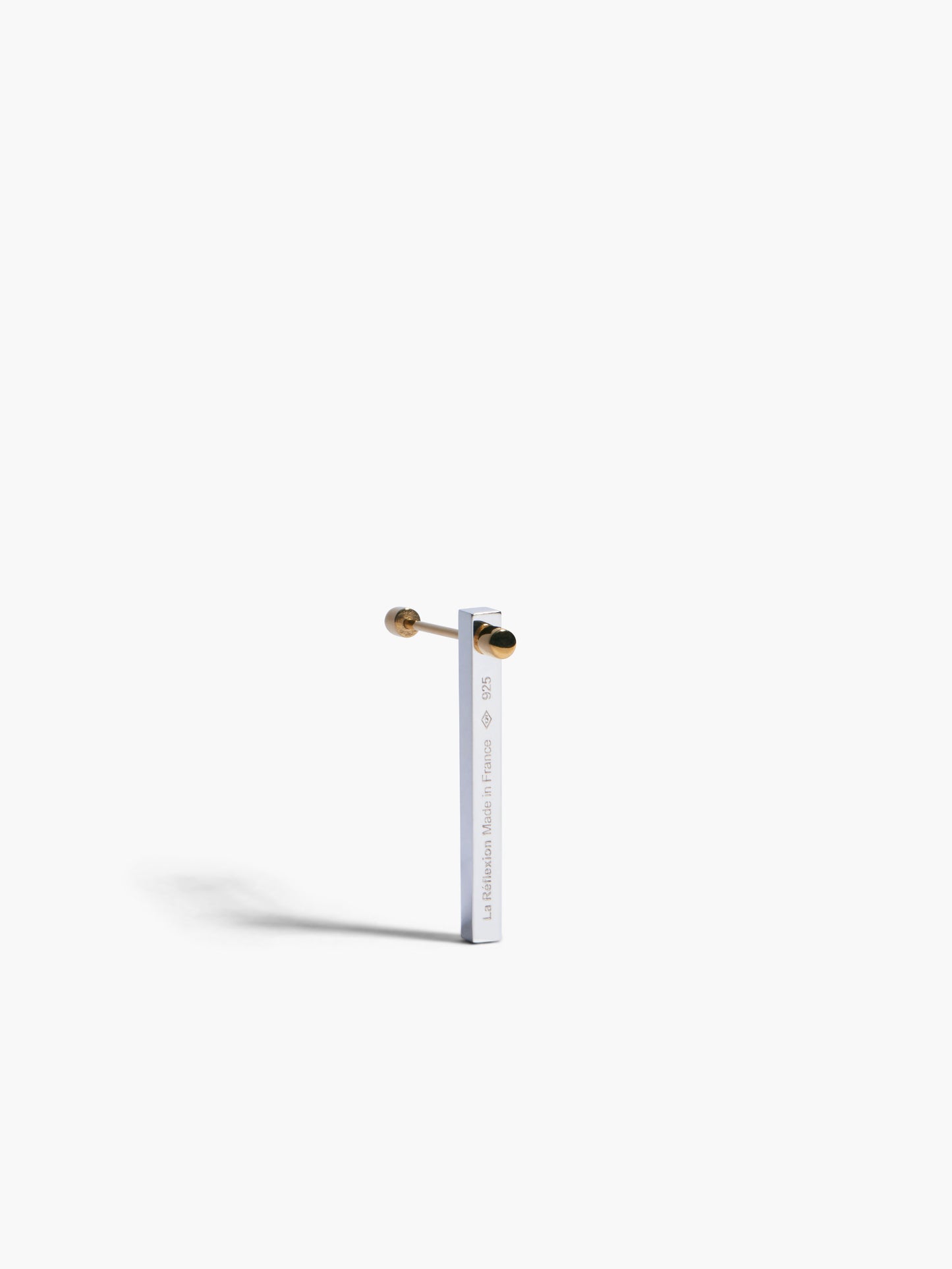 Yellow gold and silver bar earring on a white background